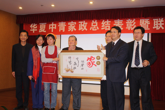 家政员王芳将亲自制作的刺绣“家”扁牌赠送给公司